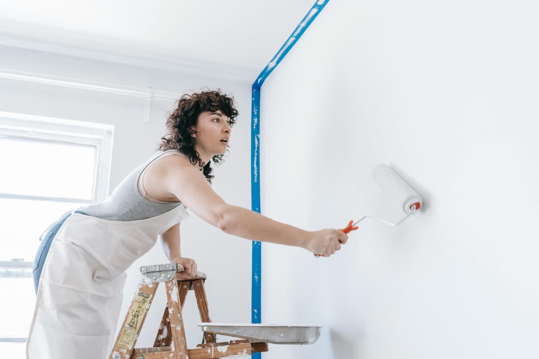 A painter rolling paint onto a wall