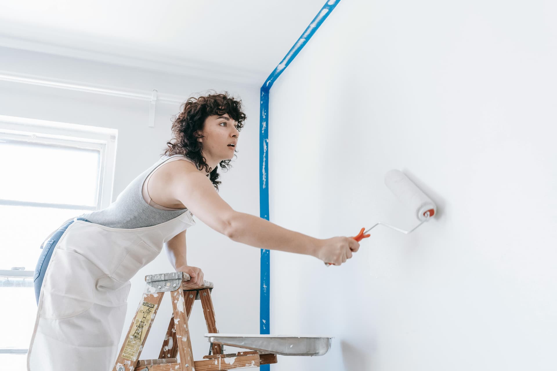 A painter rolling paint onto a wall