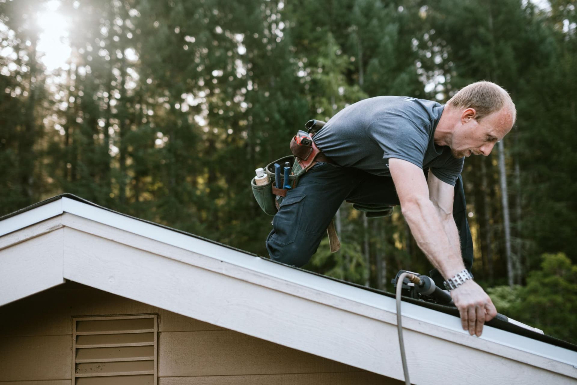 A roofer working on a shingle roof