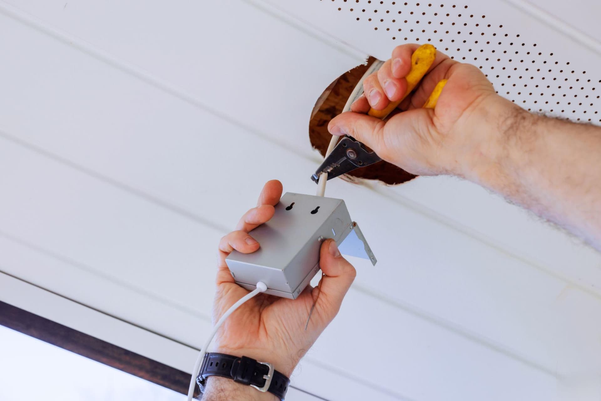 An electrician wiring a ceiling fixture